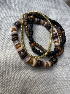 Mixed wood, glass, and clay beads. Brown, black, and gold tones. Stretch bracelet set of 4. Set includes all 4 bracelets shown. Brown Heishi Beads Bracelet, Adjustable Brown Heishi Beads, Brown Stretch Bracelet With Stackable Round Beads, Brown Stackable Stretch Bracelet With Round Beads, Brown Stackable Bracelet With Round Beads, Brown Heishi Beads Bracelet With Colorful Beads, Brown Heishi Beads Bracelets With Colorful Beads, Adjustable Brown Beaded Bracelets With Black Beads, Earthy Brown Bracelets With Wooden Beads