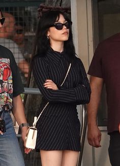 a woman with black hair and sunglasses is standing next to a man