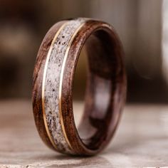 a wooden ring with antler and gold inlays sits on top of a table