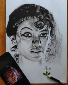 a pencil drawing of a woman's face next to a cell phone and pen