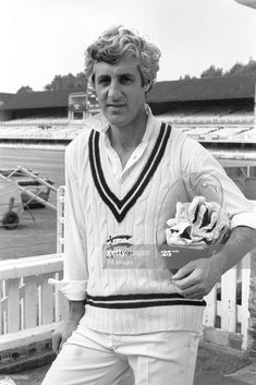 a man holding a bowl of ice cream in his right hand and wearing a sweater