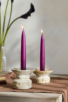 two purple candles sitting on top of a table