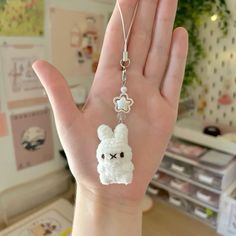 a hand holding a white crocheted animal charm