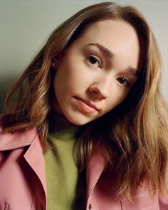 a woman in a pink trench coat looking at the camera