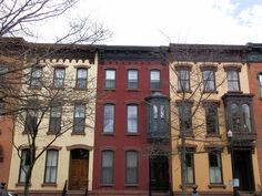 several multi - colored townhouses are lined up on the street