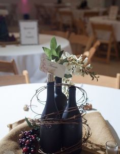 two wine bottles with flowers in them on a table at a wedding or other function