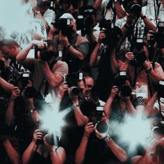 a large group of people with cameras taking pictures and recording them in front of the camera