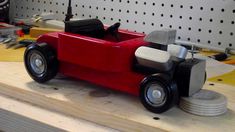 a red toy car sitting on top of a wooden table