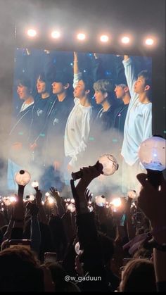 a group of people standing on top of a stage holding up their hands in the air