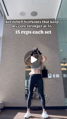 a woman standing in front of a mirror with her hands behind her head and the words kettlebell workouts that keep my core strength at 54