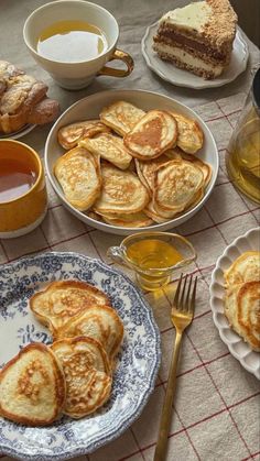 there are many different types of pancakes on the table with cups and saucers next to them