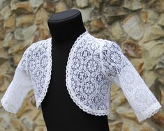 a black and white mannequin with lace on it's collar, standing next to a stone wall