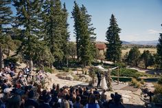 a wedding ceremony in the woods with people sitting and standing around looking at each other