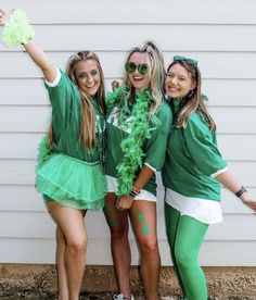 three girls dressed in green and white posing for the camera with their arms around each other