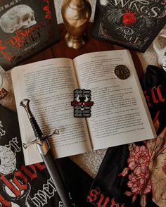 an open book sitting on top of a table next to two other books and a pen