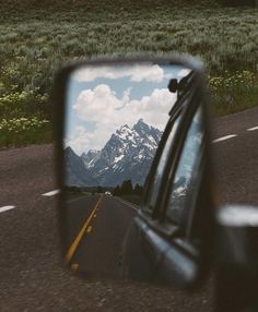 a car's side view mirror with mountains in the background