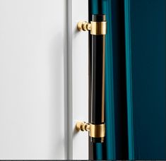 a close up of a door handle on a white and blue door with gold accents