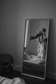 a man standing on top of a bed in front of a mirror with his reflection