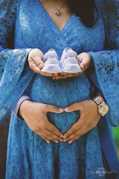 a pregnant woman holding two baby shoes in her hands