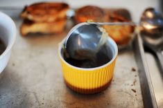 a spoon and some food sitting on a tray next to a cup with something in it