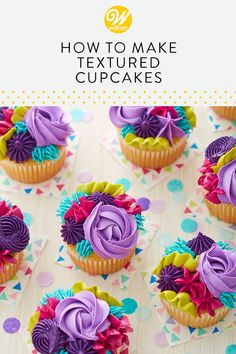 cupcakes with purple frosting and colorful flowers on them are sitting on a table