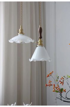 two glass lamps hanging from a ceiling in front of a window with white drapes