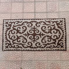 a door mat on the floor with an intricate design in brown and white color scheme