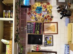 a kitchen area with various items hanging on the wall and shelves above it that have pictures, magnets, and other decorations