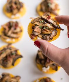 a person is holding up some food to the camera and it looks like they have mushrooms on them