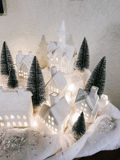 small white houses and trees are lit up in the snow with fairy lights on them