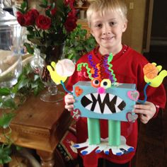 a young boy holding up a paper cut out of a monster