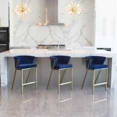 a kitchen with marble counter tops and blue velvet bar stools in front of an oven