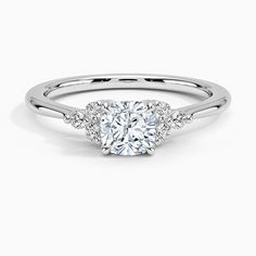 a diamond engagement ring with three stones on the band and an oval shaped center stone