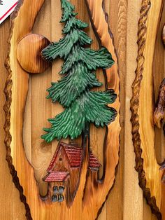 two wooden plaques with pine trees on them, one has a house and the other is a cabin