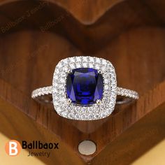 a blue and white diamond ring sitting on top of a wooden box