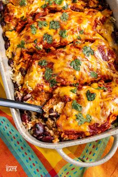 a casserole dish with meat, rice and vegetables in it on a colorful table cloth