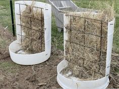 two white containers filled with hay sitting in the grass