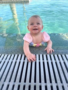 a baby sitting on the edge of a swimming pool