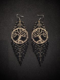 two pairs of beaded earrings with black and white designs on the front, one is shaped