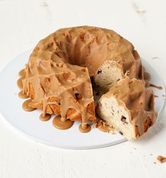 a bundt cake with chocolate frosting on a white plate next to a slice cut out