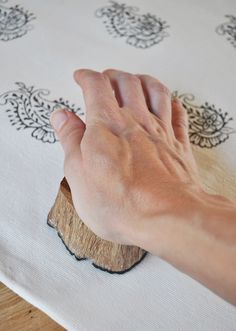 a person's hand on top of a piece of wood that is sitting on a table