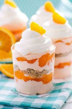 two desserts with orange slices and whipped cream in them on a blue checkered cloth