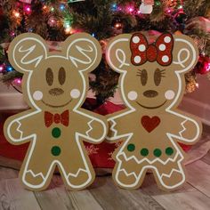 two gingerbread cut outs standing next to a christmas tree