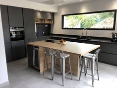 a kitchen with an island and bar stools in the center, next to a window