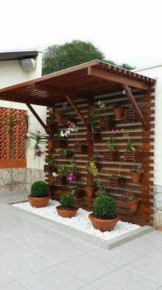 a wooden structure with potted plants on the side and a wall behind it that is made out of wood planks