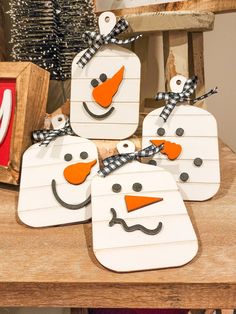 four snowmen made out of wood sitting on top of a table