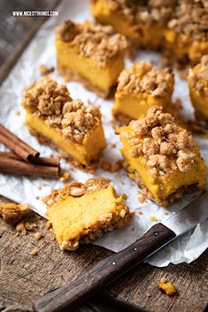 several pieces of dessert sitting on top of a piece of paper next to cinnamon sticks