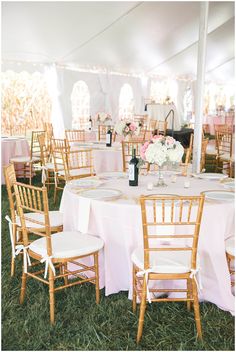 a table set up with pink and white linens for an outdoor wedding reception in the grass