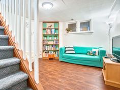 a living room filled with furniture and a book shelf next to a stair case in front of a tv