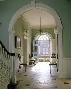 an open door leading to a hallway with two chairs on either side and another set of stairs